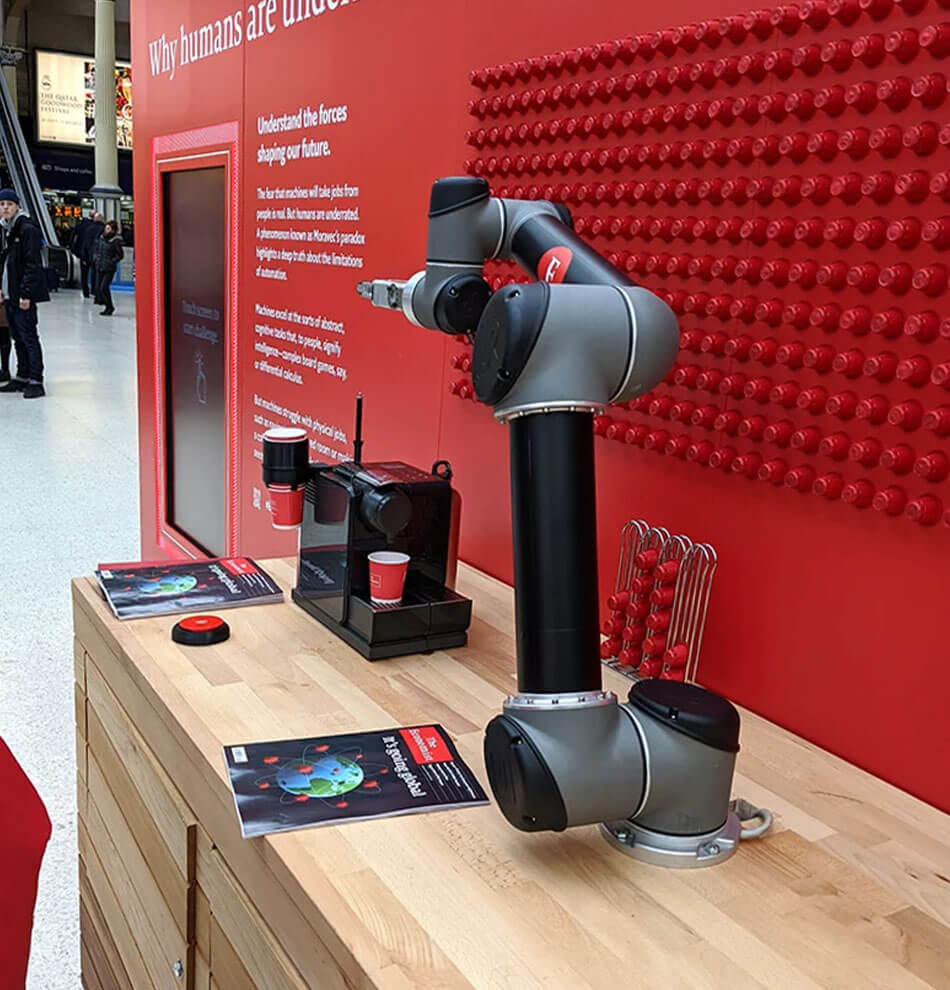 Angled camera shot of robot arm and Economist display