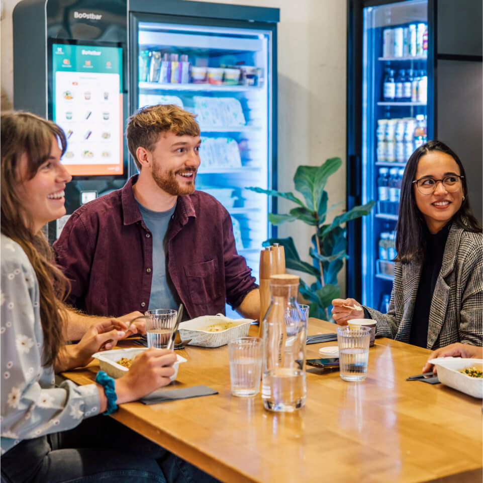 Group around table eating with Boost machines in the background