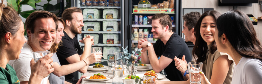 Group around table eating with Boost machines in the background