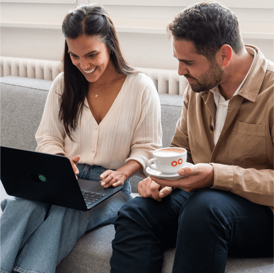 A man and a woman working on a laptop drinking coffee